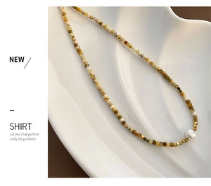 Detail of natural stone beaded necklace with a central freshwater pearl on a white tray