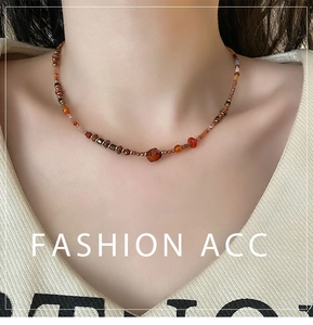 Detailed view of beaded carnelian necklace with vintage charms and faceted center stone