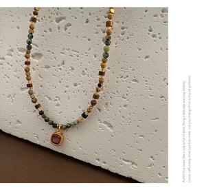 Detail of handcrafted stone necklace with red zircon pendant and mixed gemstone beads
