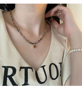 Close-up of vintage beaded necklace with red gemstone pendant worn by a model
