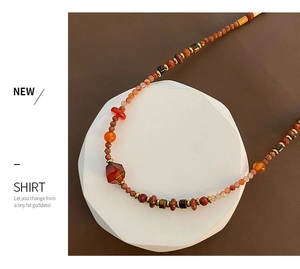Detail of red agate necklace with warm-toned Czech beads and metallic spacers on white base