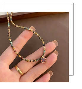 Macro detail of handmade beaded necklace with red zircon pendant and natural stones