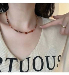 Detail of beaded red agate necklace featuring mixed vintage gemstones on a female model