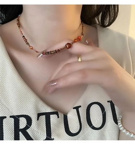Detail of red agate bead necklace with hexagonal amber center on a female model