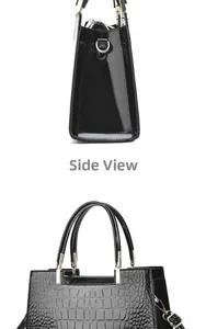 Detail view of black patent leather handbag with crocodile embossed texture and side D-ring