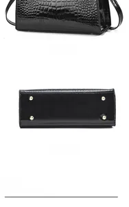 Detail of black crocodile texture handbag with gold protective studs and glossy finish