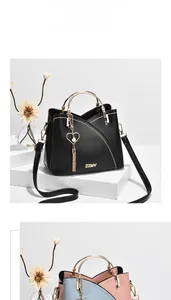 Detail of minimalist leather bag featuring gold arc handles and heart tassel charm