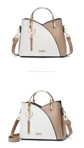 Detail of a chic cream patchwork handbag featuring a circular metal handle and heart tassel