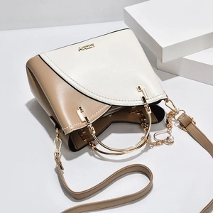 Elegant beige two-tone handbag with gold metal handles and a pearl charm pendant