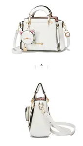 Detail view of white PU leather handbag featuring cute cat-shaped pendant and gold hardware
