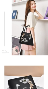 Detailaufnahme der Blumenstickerei und Perlen-Schleifenanhänger an schwarzer Handtasche