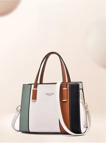 Detail of color-block leather handbag featuring double handles and a white shoulder strap