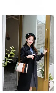 Outdoor shot of a multi-color paneled leather handbag styled with a black trench coat