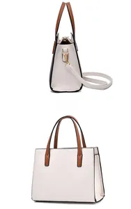 Close-up of cream faux leather tote bag with brown handles and gold hardware details