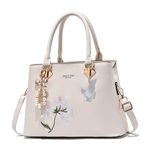 Elegante cremefarbene Handtasche mit Blumenstickerei und dekorativem Schmetterlingsanhänger