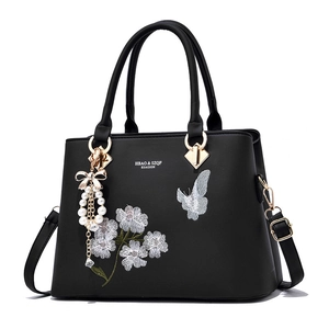 Elegante schwarze Handtasche mit Blumenstickerei und Perlen-Schleifen-Anhänger-Detail