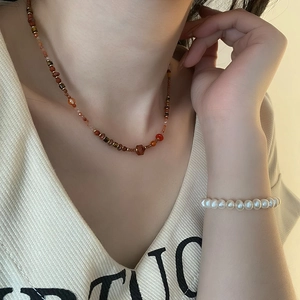 Ethnic red agate necklace and freshwater pearl bracelet worn with a V-neck shirt
