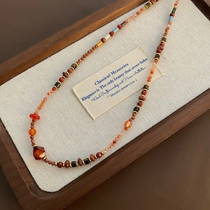 Bohemian beaded necklace with red agate and quartz stones in a vintage jewelry tray