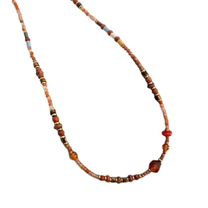Ethnic style necklace featuring red agate, natural stones, and golden beads on white background