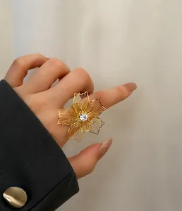 Detalle de un gran anillo de flor hueca dorada con circón en el dedo de una modelo