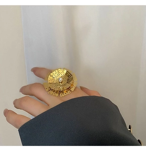 Dettaglio dell'anello a fiore dorato con petali traforati e perla centrale bianca