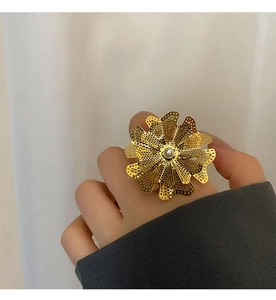 Dettaglio di un grande anello a fiore in oro con petali traforati e una perla centrale