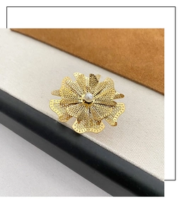 Dettaglio anello fiore dorato con petali in filigrana traforata e perla centrale