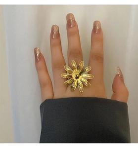 Macro di un grande anello a fiore dorato con petali testurizzati indossato