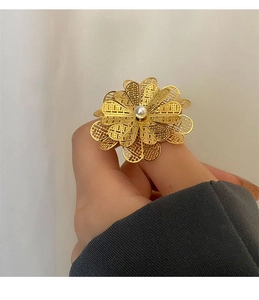 Vista dettagliata di un anello a fiore in filigrana d'oro con perla al dito