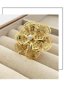 Vista dettagliata dell'anello a fiore traforato con petali dorati e perla centrale