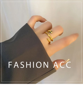 Close-up of gold snake ring with green stone eyes worn with a dark grey suit sleeve