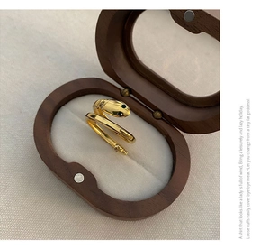 Detail of gold snake ring with gemstone eyes presented in a premium wooden jewelry box