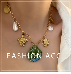 Macro shot of gold sea turtle, shell and pearl charms on a summer beach style necklace