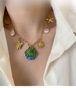 Detail of gold chain necklace featuring seashell, starfish, turtle and pearl charms