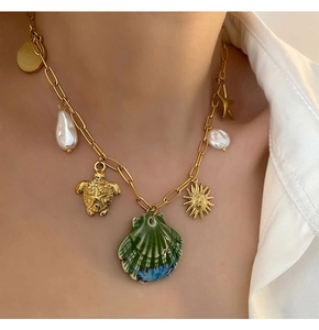 Detail of a gold ocean necklace with turtle, starfish, and enamel shell pendant on a model
