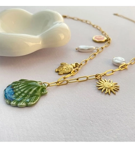 Detail of beach style necklace with gold shell, pearl charms and turtle pendant