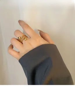Close-up of golden triple-layer spiral ring with heart accents on a hand