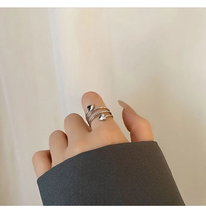 Close-up of heart-shaped silver ring on model's finger with minimalist spiral design