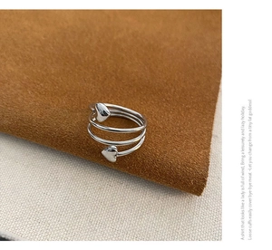 Detailed view of silver triple-layered wrap ring featuring heart-shaped ends and polished finish