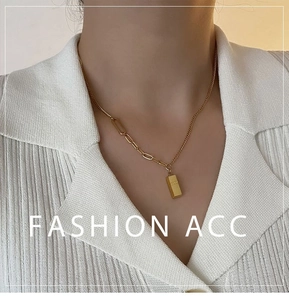 Détail du collier pendentif lingot d'or avec chaîne asymétrique sur tricot blanc