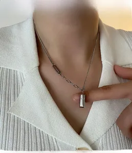 Détail du collier avec pendentif rectangulaire argenté et chaîne à maillons asymétriques