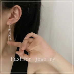 Close-up of elegant long tassel earrings with five sparkling crystals on gold chains