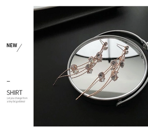 Detailed macro view of rose gold tassel earrings with zircon stones on a mirror surface