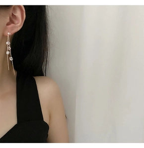 Close-up of elegant long gold tassel earrings with zircon crystals worn by a model