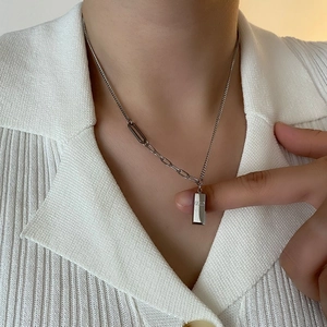 Collier pendentif barre argentée avec chaîne asymétrique sur modèle en chemise