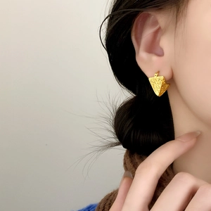 Gold textured hollow triangle earrings featuring a vintage metallic finish on a model