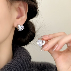 Elegant heart-shaped zircon stud earrings in silver settings shown on a model's ear