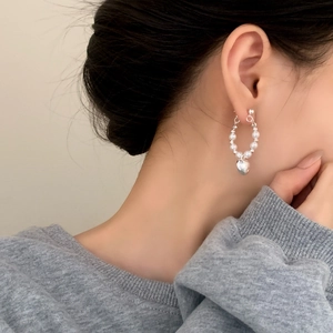 Minimalist pearl hoop earrings with heart charm shown on a model for a refined look