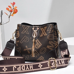 Braune Beuteltasche mit Buchstabendruck, Katzenschloss und breitem Jacquard-Gurt auf Grau