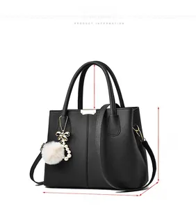 Detailed view of black litchi pattern leather handbag with gold hardware and pearl charm